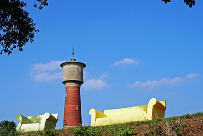 Low angle view of lighthouse amidst buildings against sky