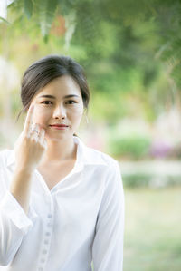 Portrait of young woman showing her index finger while standing at park