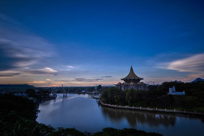 Bridge over river in city against sky during sunset