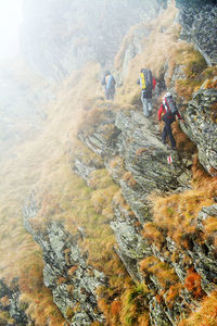 Rear view of hikers walking on mountain during foggy weather