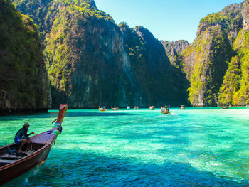 People on boat in sea against mountains