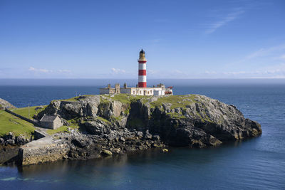 Lighthouse by sea against sky