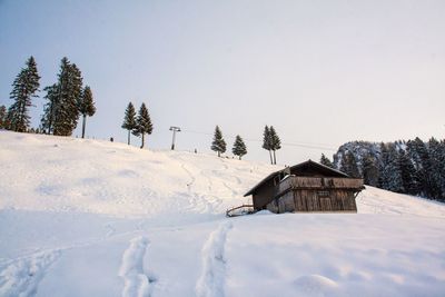 House by trees against clear sky during winter