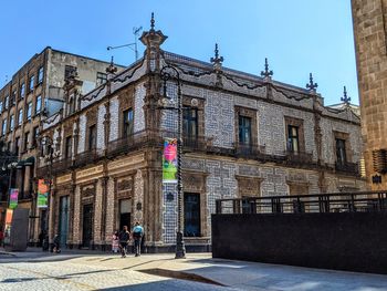 People on street against buildings in city