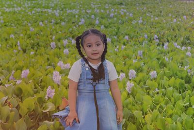 Portrait of cute girl against flowers on field