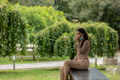 Attractive teen girl sitting in a park and having coffee. copy space