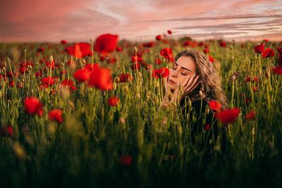 Close-up of young woman in red poppy flowers in field