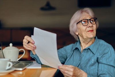 Smiling senior woman holding document in cafe