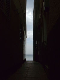 Empty alley amidst buildings against sky