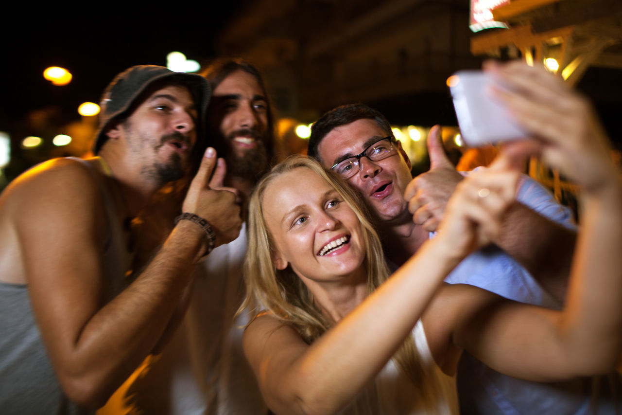 Cheerful friends taking selfie at night