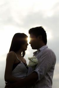 Young couple standing against sky