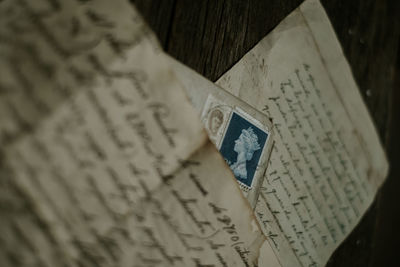 From above shabby aged letters and envelope with postage stamp placed on timber table in dark room