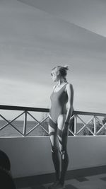 Full length of woman wearing swimsuit standing in balcony against sky
