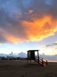 Lifeguard hut on beach against sky during sunset