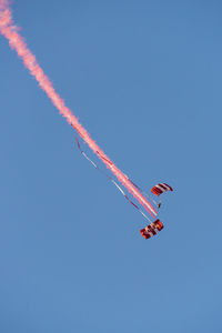 Low angle view of airplane flying against clear blue sky