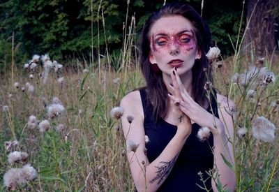 Portrait of woman with eye mask sitting on grassy field