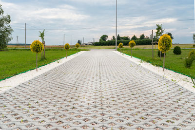 Empty road amidst field against sky