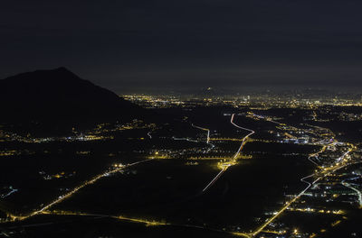 Illuminated cityscape by sea against sky at night