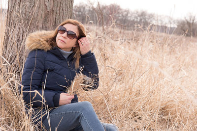 Mature woman wearing sunglasses while sitting on field