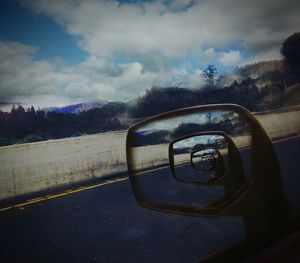 Close-up of car on road against cloudy sky