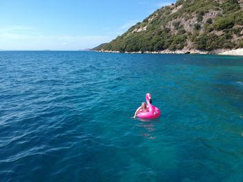 Woman swimming with pink inflatable ring in sea during sunny day