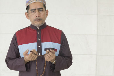 Portrait of man with necklace standing in mosque