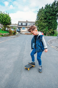 Full length of boy skateboarding on road