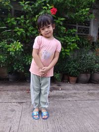 Portrait of young woman standing against plants