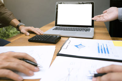 Midsection of man using laptop on table