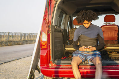 Young latino surfer with afro hair talks on a mobile phone in the caravan person