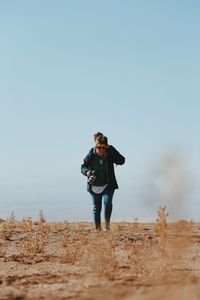 Young woman with camera walking on field