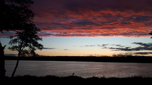 Silhouette trees on field against romantic sky at sunset