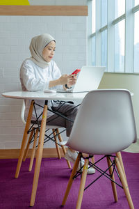 Woman using phone while sitting on chair