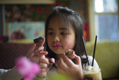Cute girl with sister eating muffin at restaurant