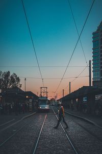 Railroad tracks in city against clear sky during sunset