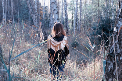 Rear view of woman with dog sitting in forest