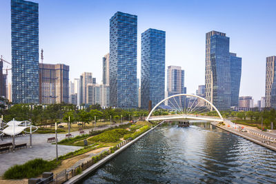 Bridge over river amidst buildings in city against sky