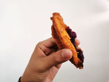 Close-up of hand holding ice cream over white background