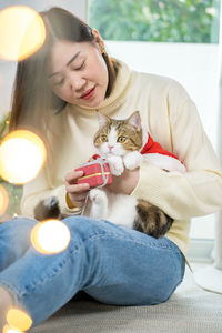 Asian woman smile and happy during play and clothing red santa blanket to her cat