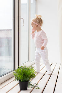 Side view of young woman standing by window