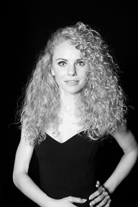 Portrait of woman with curly hair against black background