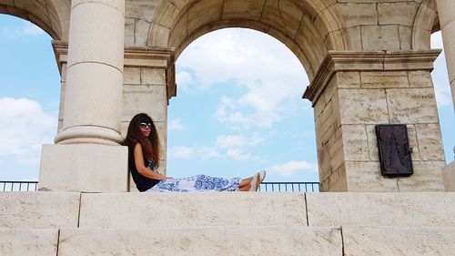 Low angle view of woman sitting against sky