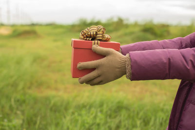 Woman holding gift box on field