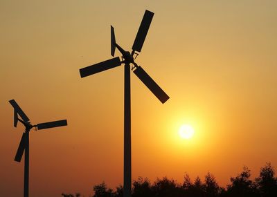 Silhouette windmills against sky during sunset