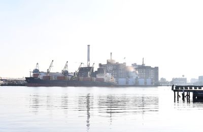 Commercial dock by sea against clear sky