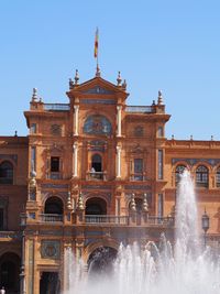 Fountain in front of building against clear sky