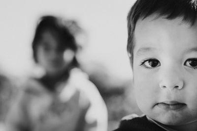 Close-up portrait of cute baby boy with sister in background