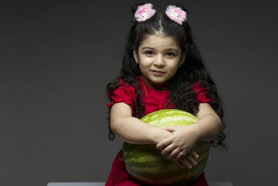 Portrait of smiling young woman holding gift against black background