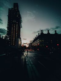 City street and buildings against sky at dusk