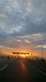 Cars on street against sky during sunset